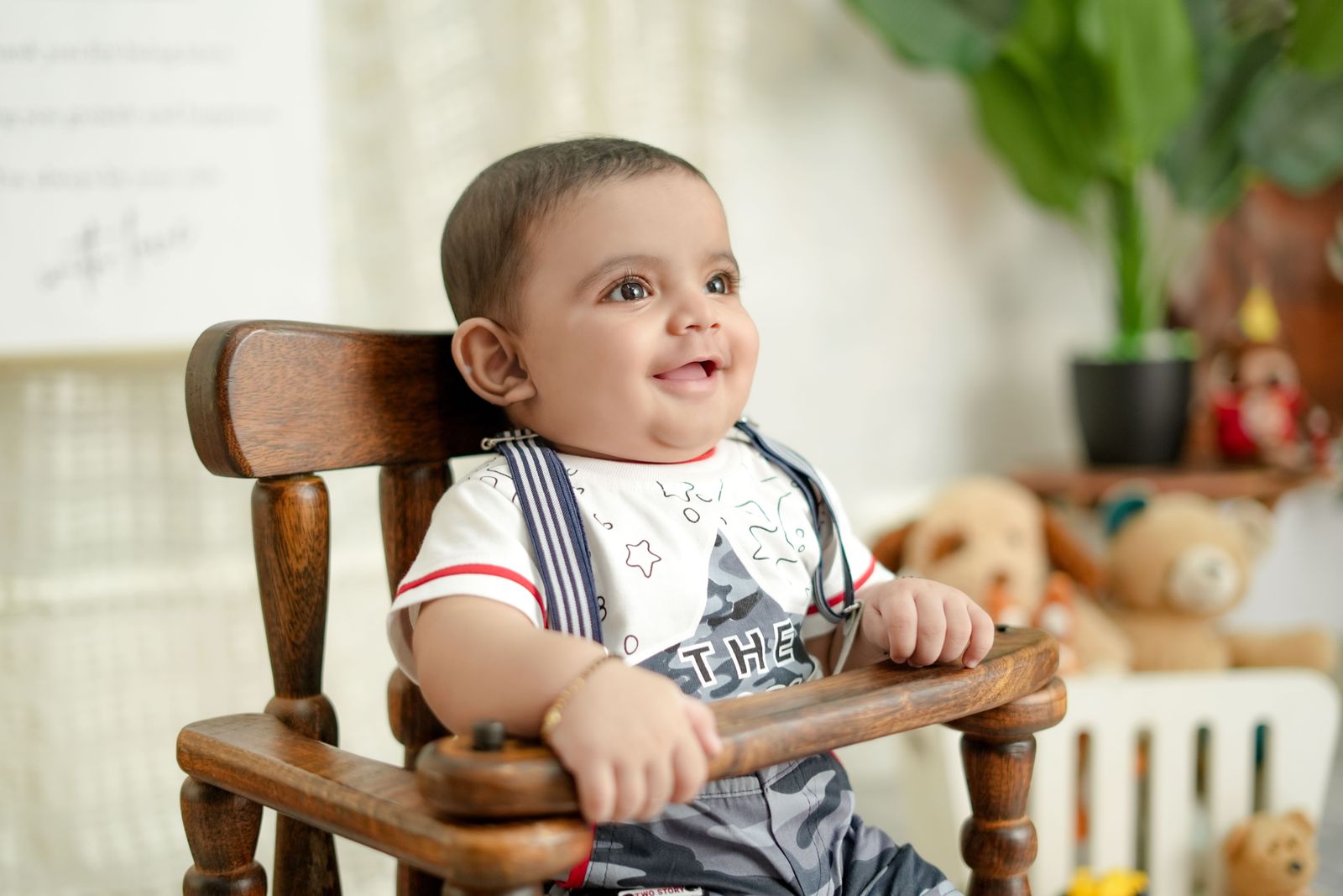 Smiling baby sitting in a dark wooden high chair with a front tray bar