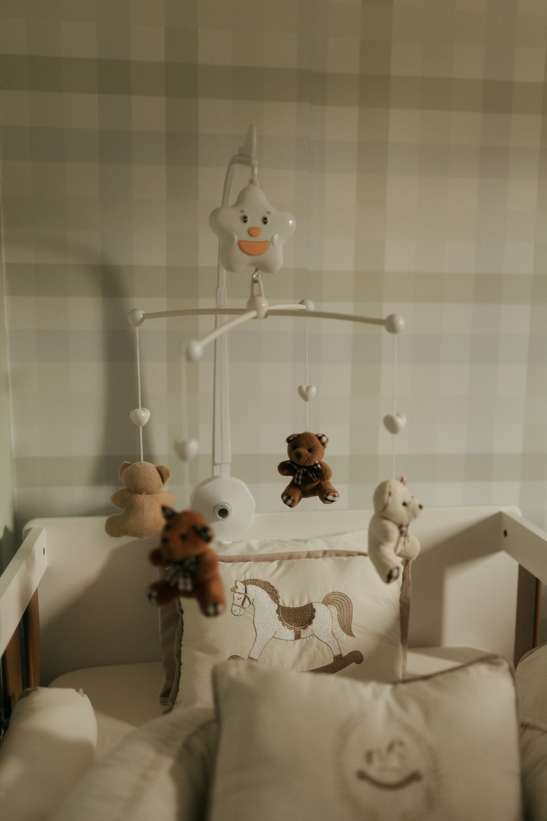 Soft teddy bear mobile hanging over a white crib