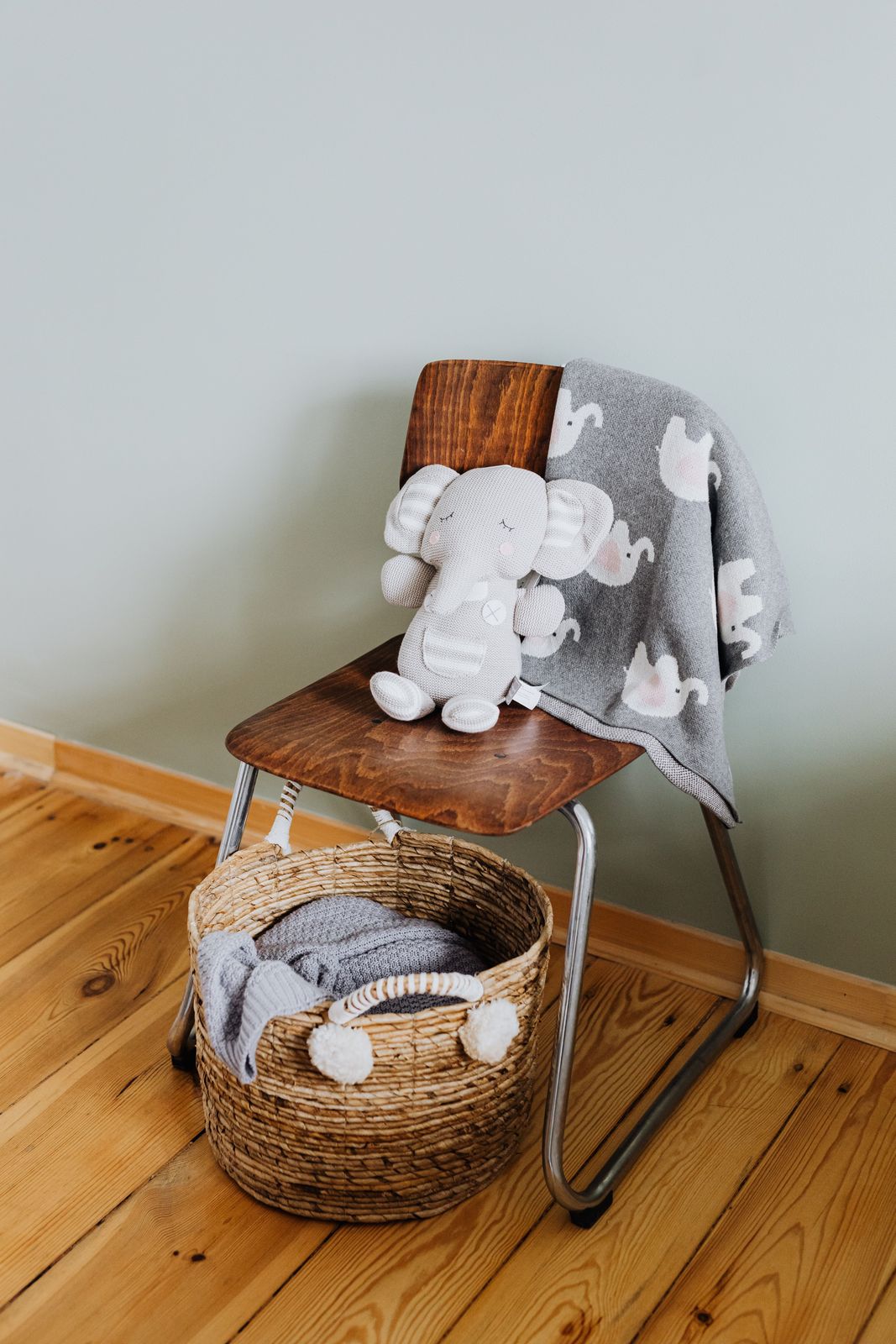 Bentwood kids chair with a knitted elephant toy and elephant blanket above a woven storage basket