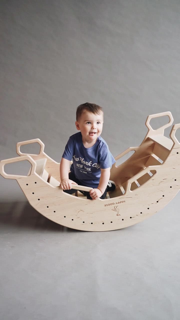 Toddler playing in a natural wooden rocking arch